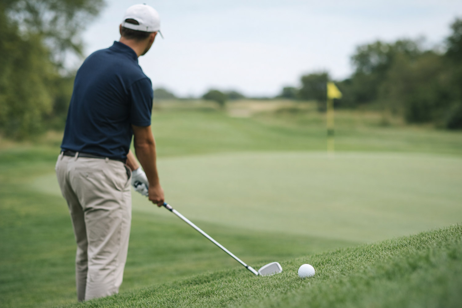 Golfspelare förbereder slag på fairway med fokus på klubba och boll.